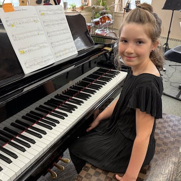 teen boy in grey hoodie sitting at grand piano